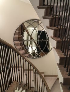 Large Circular Hand Polished Window Mirror displayed in our clients stairwell area to reflect their beautiful stairway detail